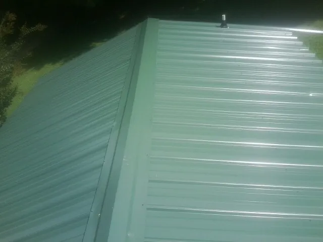New green metal panels meeting at the ridge of a roof — Flat Roof Repair work by our crew in Pleasant Hill