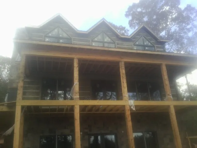 Dormers and porch framing on a large log home under construction — Roof Coating work by our crew in Pleasant Hill